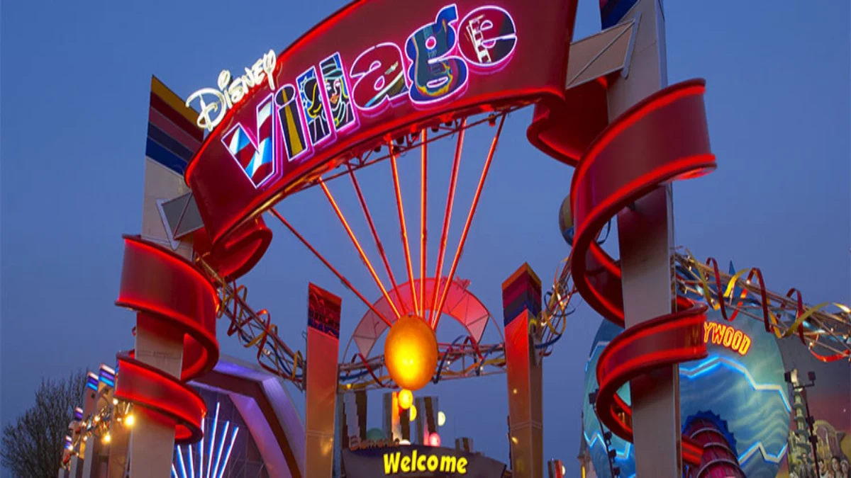 The glowing entrance sign of Disney Village at night