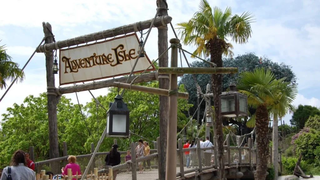 Wooden rope bridge entrance to Adventure Isle at Disneyland Paris, with palm trees and lanterns