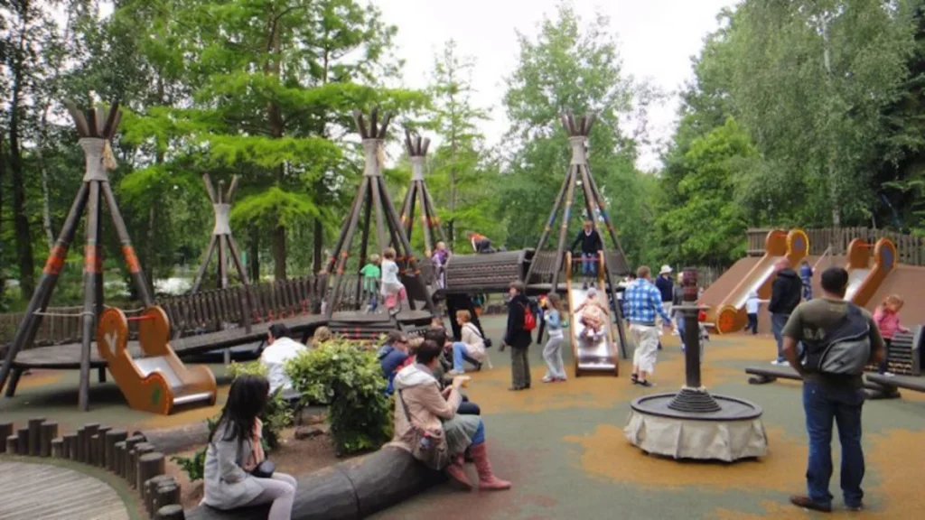 Families and children play on slides and wooden climbing structures at Adventure Isle in Disneyland Paris