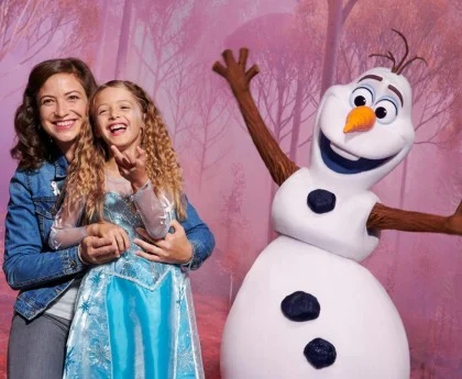 A mother and daughter take a photo with Olaf from Frozen