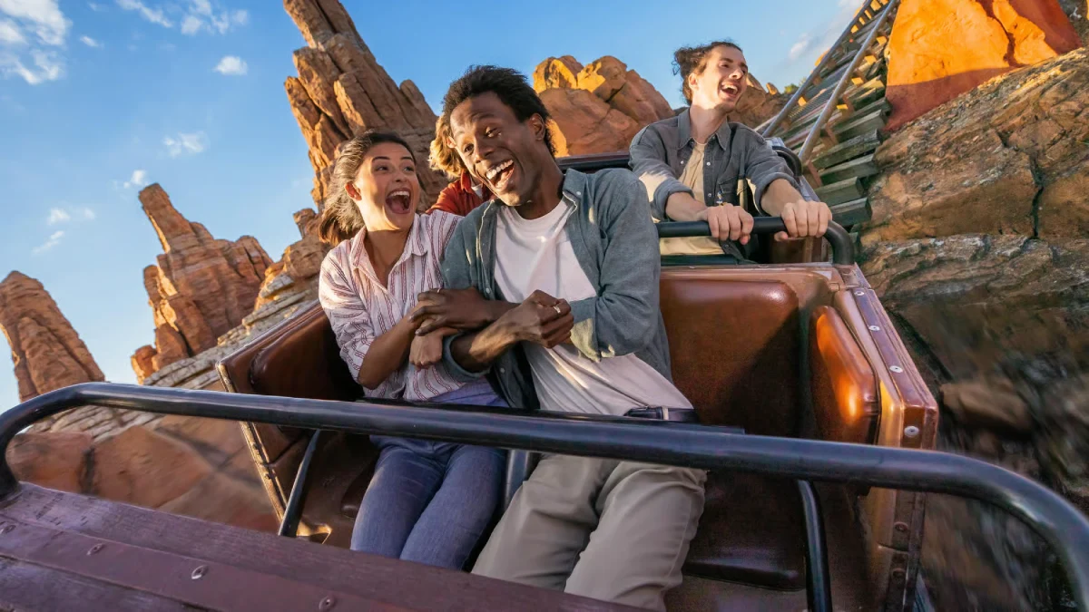 A group of friends enjoy a thrilling roller coaster ride at Disneyland® Paris, smiling and laughing in excitement