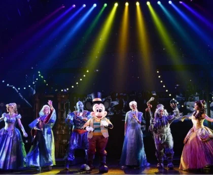 Mickey Mouse and Disney characters perform under rainbow stage lights