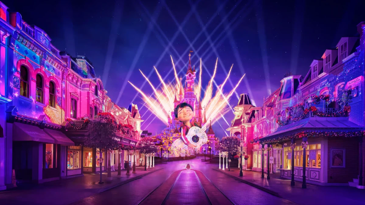 The Disneyland® Paris Castle lit up with colorful lights and fireworks during a night show, with Main Street illuminated