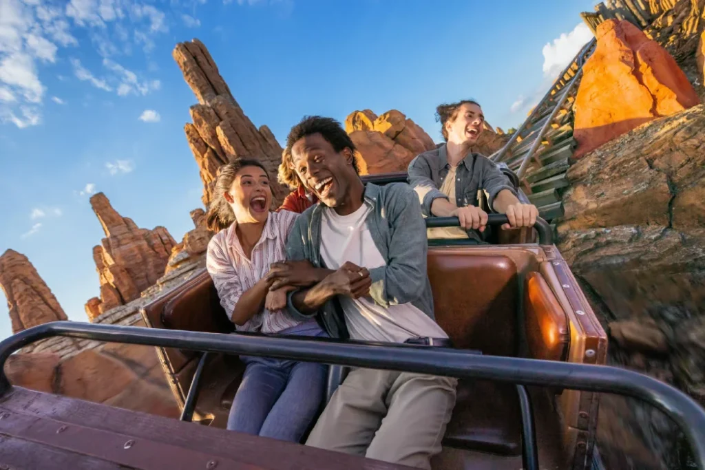 A group of friends enjoy a thrilling roller coaster ride at Disneyland® Paris, smiling and laughing in excitement