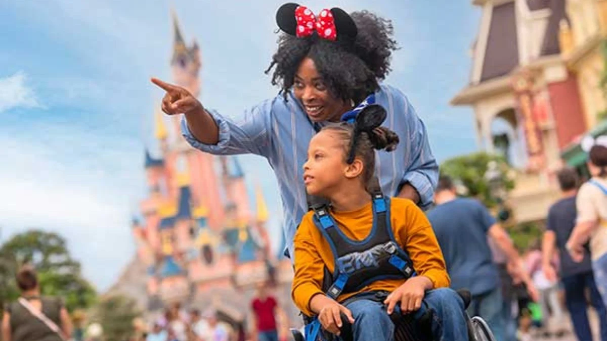 disneyland-wheelchair-access A mother and child in a wheelchair enjoy Disneyland Paris with the castle in the background
