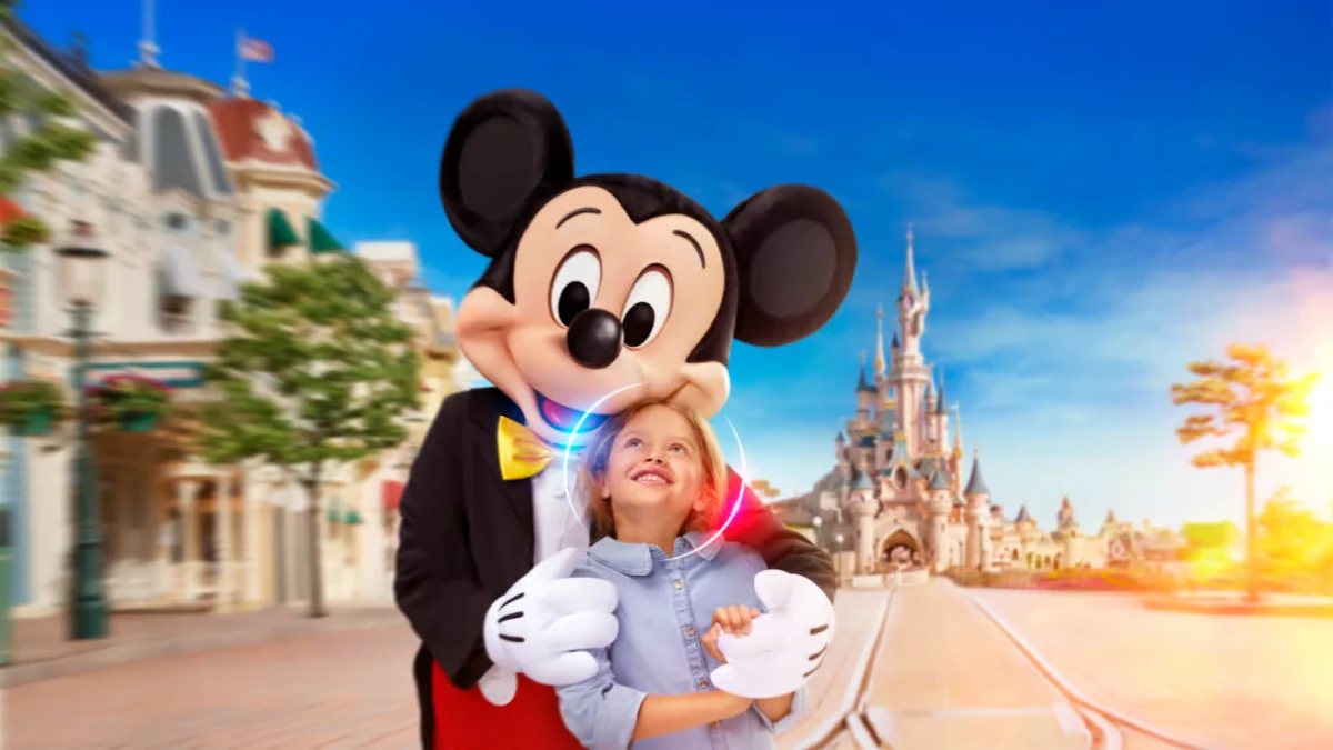 Mickey Mouse hugging a smiling child with the Disneyland castle in the background on a sunny day