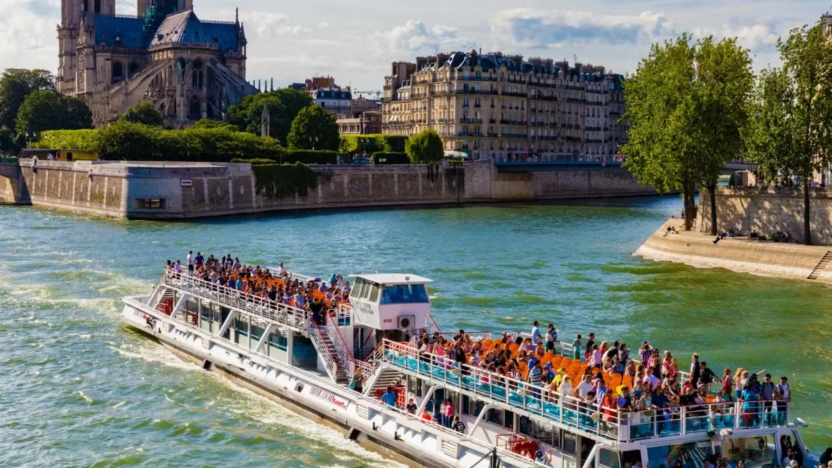seine-river-cruise-notre-dame Sightseeing boat full of tourists sailing on the Seine River with Notre Dame Cathedral in the background